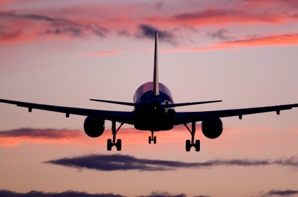 Airplane taking off into sunset sky